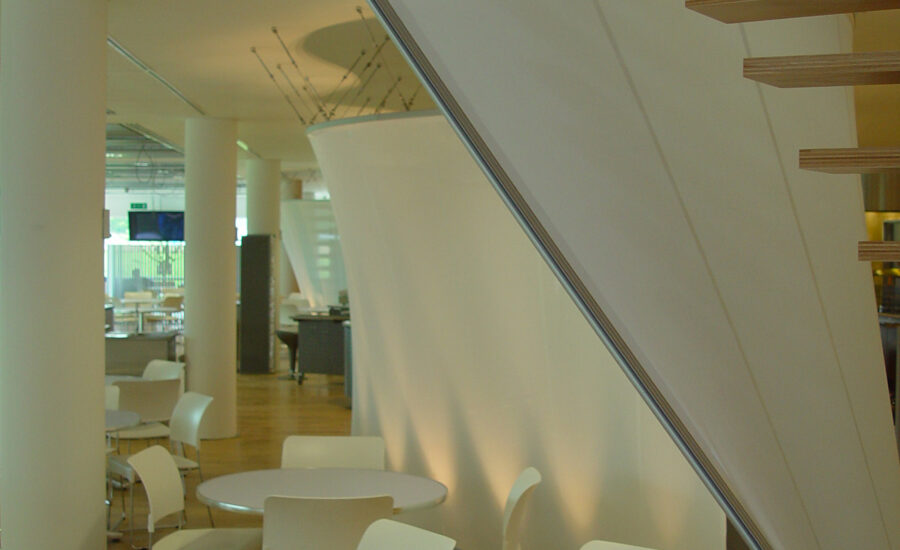 Floor up-lighters illuminating the curved fabric screen in the BT Leavesden Park staff restaurant
